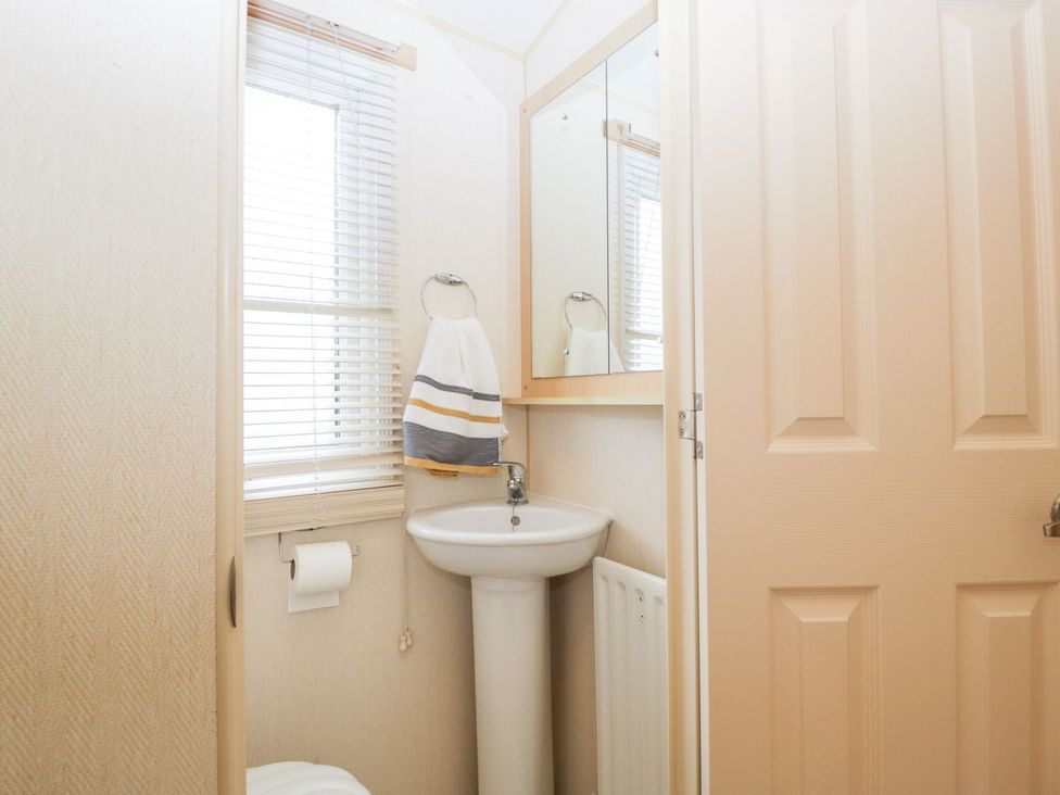 A bathroom with a sink, mirror, and towel rack at The Hideaway in Portesham