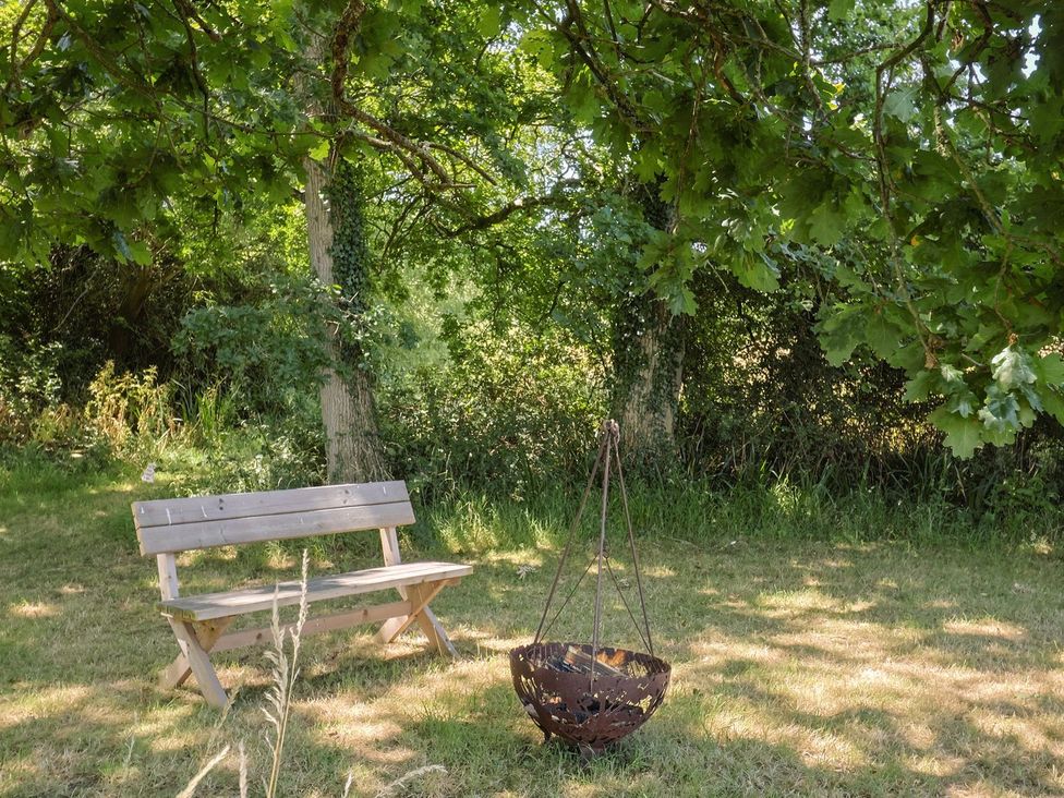 A garden with a bench and a fire pit at The Hideaway in Portesham