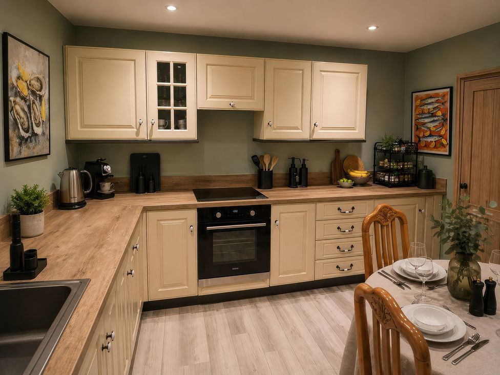 A kitchen with cabinets, oven, and dining table at Haregate House in Leek