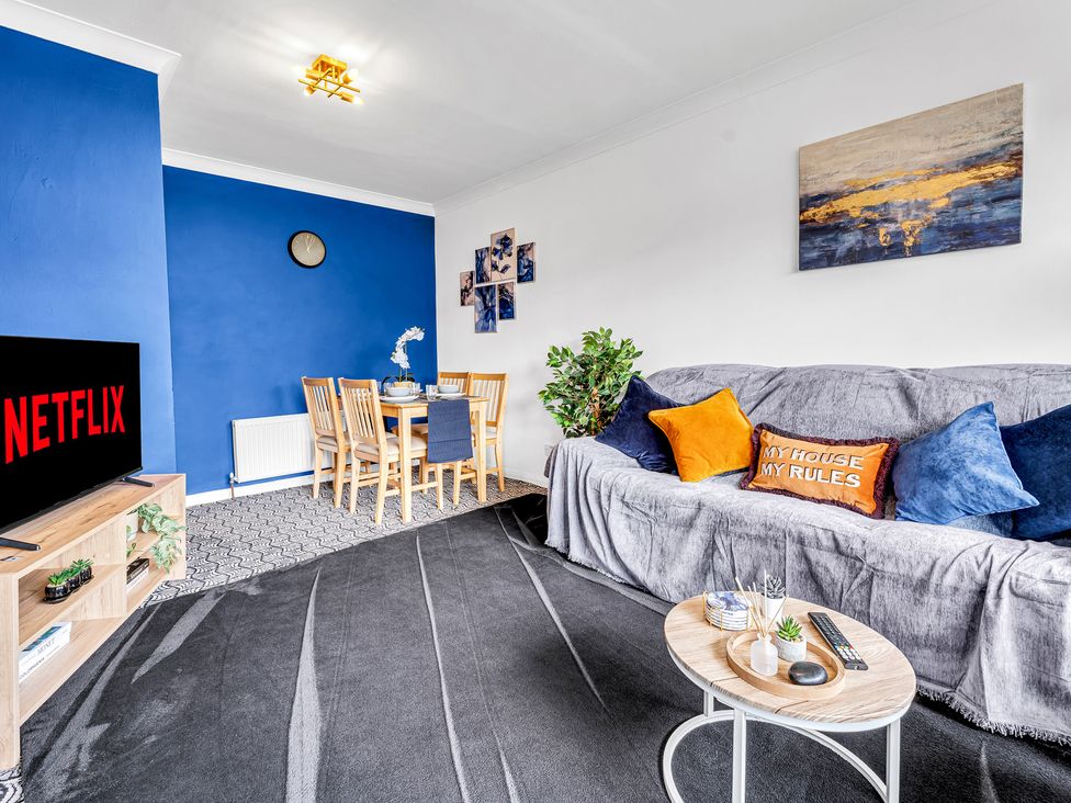 A living room with a sofa and dining area at Mallory House in Stoke-on-Trent