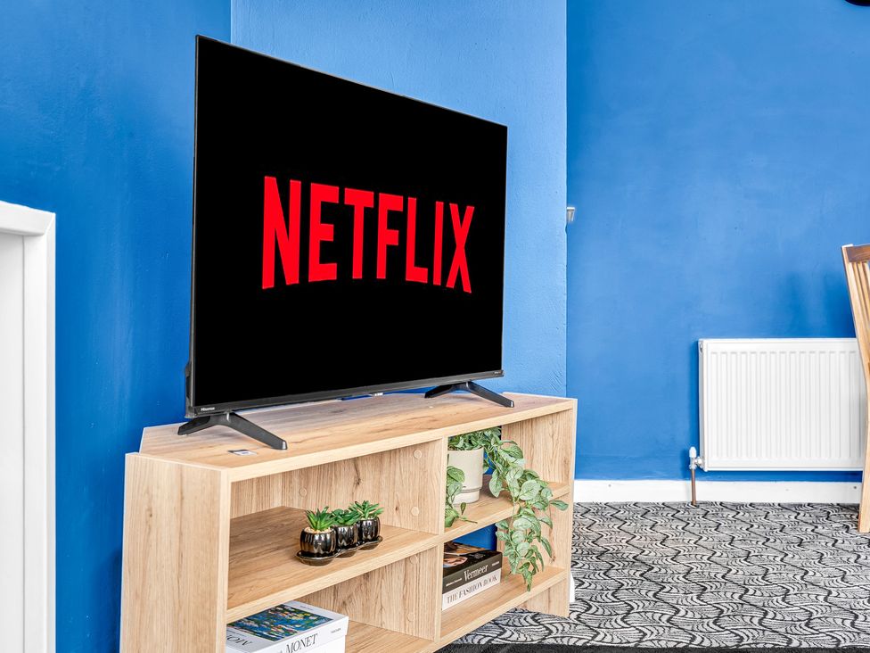A living room with a television displaying Netflix at Mallory House in Stoke-on-Trent