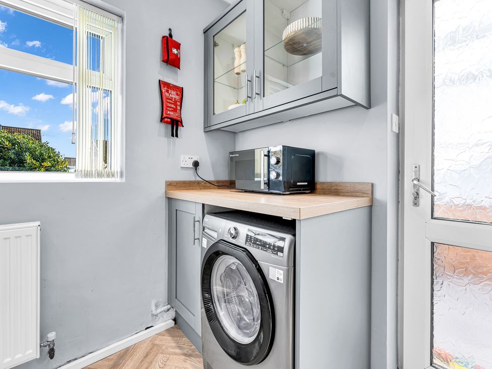 A laundry room with a washing machine and microwave at Mallory House in Stoke-on-Trent