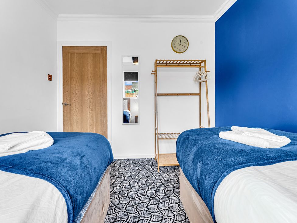 A bedroom with two beds and a clothes rack at Mallory House in Stoke-on-Trent