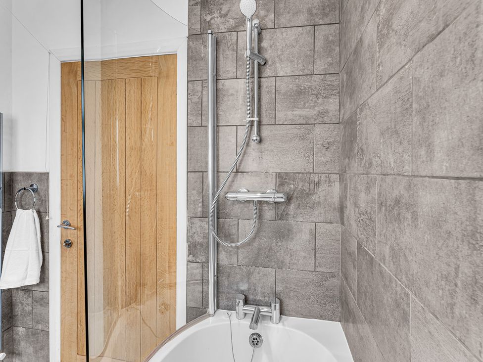 A bathroom with a bathtub and shower setup at Mallory House in Stoke-on-Trent