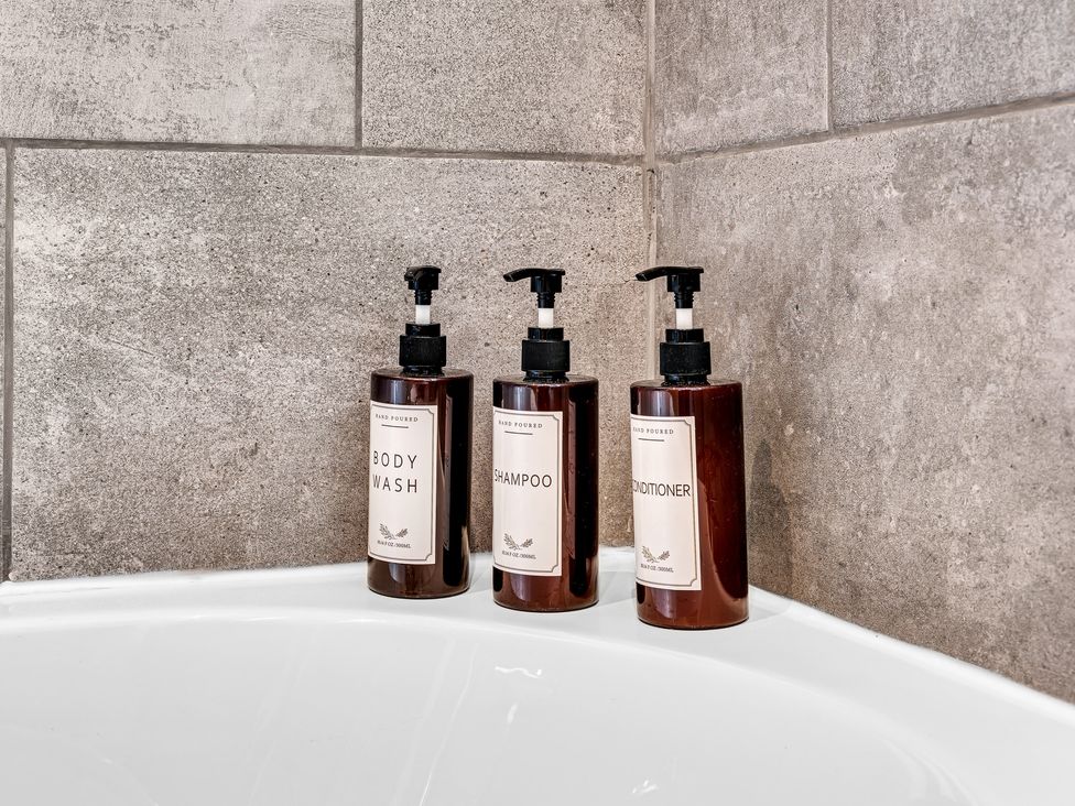 Bottles of body wash, shampoo, and conditioner in a bathroom at Mallory House in Stoke-on-Trent
