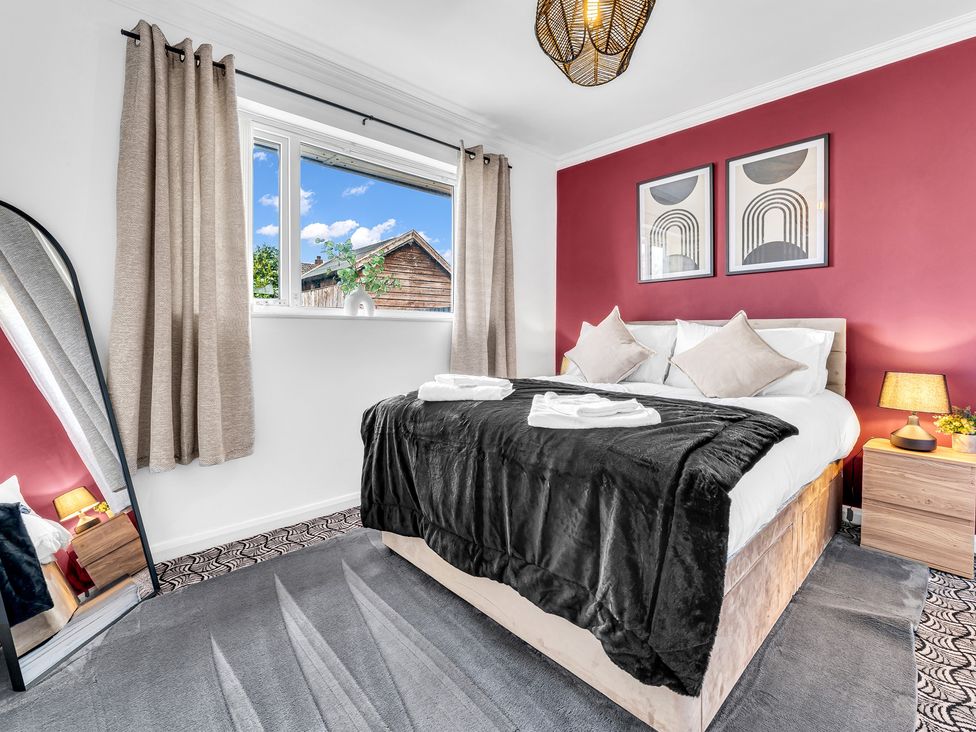 A bedroom with a bed, mirror, and side table at Mallory House in Stoke-on-Trent