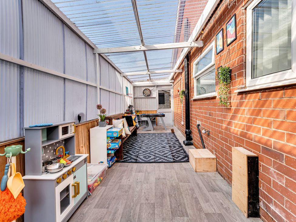 A conservatory with a play kitchen, table, and chairs at Mallory House in Stoke-on-Trent