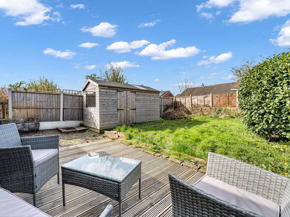 A garden with a shed, wooden fence, and outdoor furniture at Mallory House in Stoke-on-Trent
