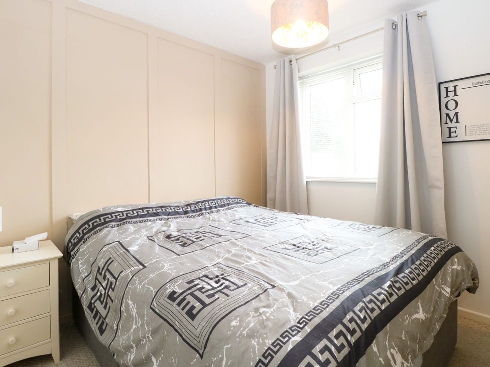 A bedroom with a bed and a bedside table at Leaf Lodge in Hemsby