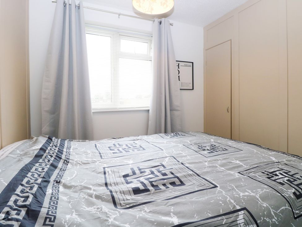 A bedroom with a bed and curtains at Leaf Lodge in Hemsby