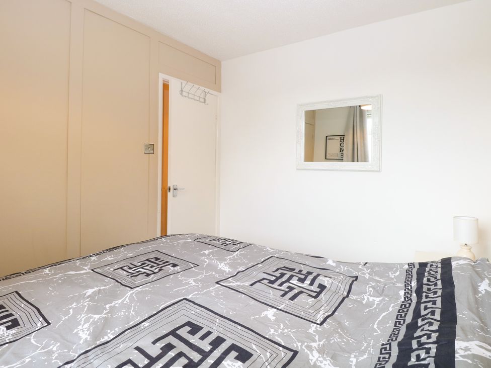A bedroom with a bed and mirror at Leaf Lodge in Hemsby