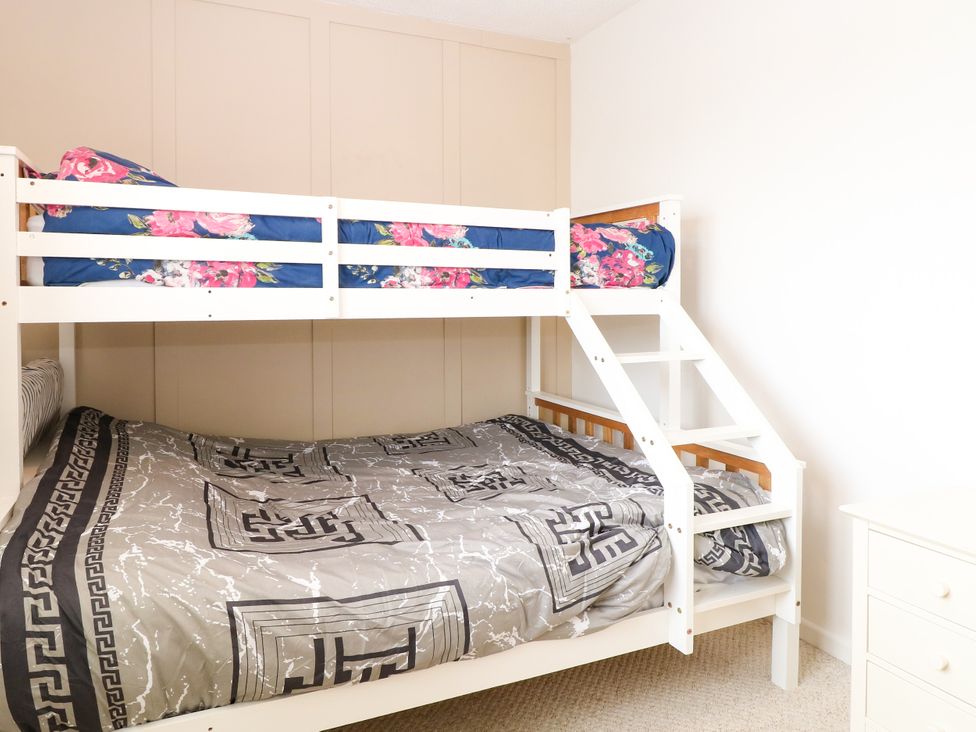 A bedroom with a bunk bed and a bedside table at Leaf Lodge Hemsby