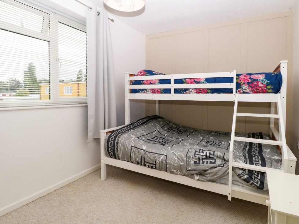 A bedroom with a bunk bed and window at Leaf Lodge in Hemsby
