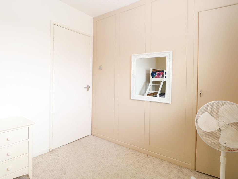 A bedroom with a mirror and cabinet at Leaf Lodge in Hemsby