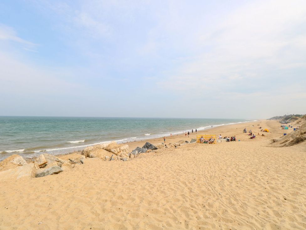 A beach with people and rocks at Leaf Lodge in Hemsby