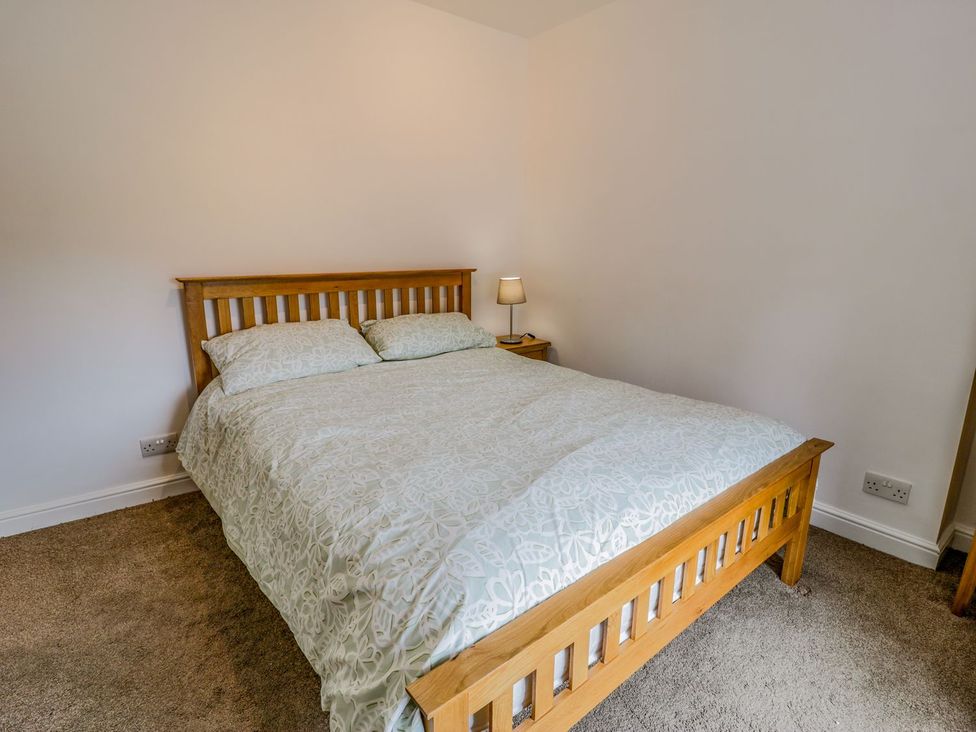A bedroom with a bed and lamp at Awelfryn in Betws-y-Coed