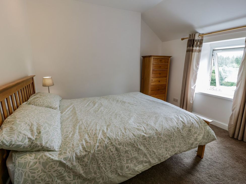 A bedroom with a bed, dresser, and window at Awelfryn in Betws-y-Coed