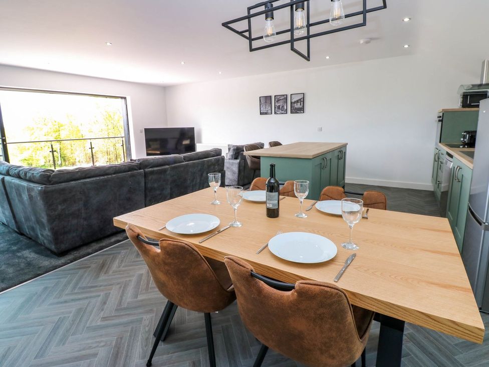 A dining table with glasses and a bottle at Sycamore Cottage in Frizington