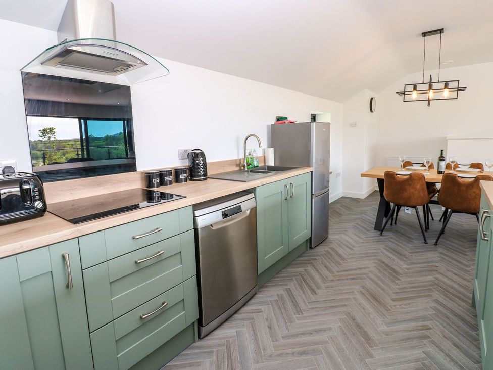 A kitchen with appliances and dining area at Sycamore Cottage in Frizington