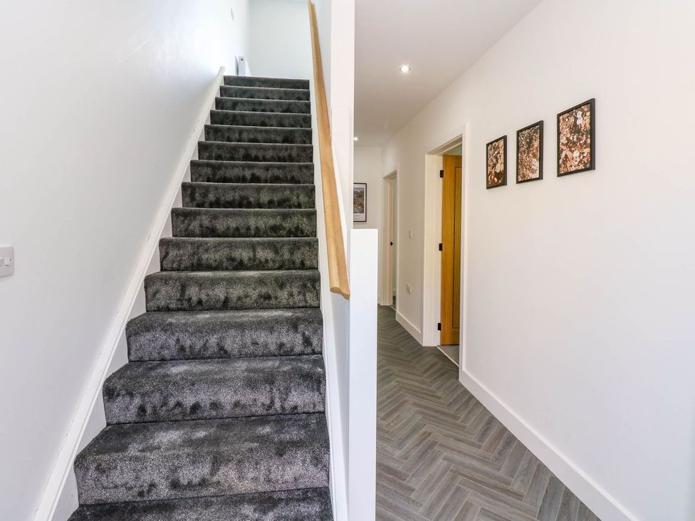 A hallway with staircase and pictures at Sycamore Cottage in Frizington