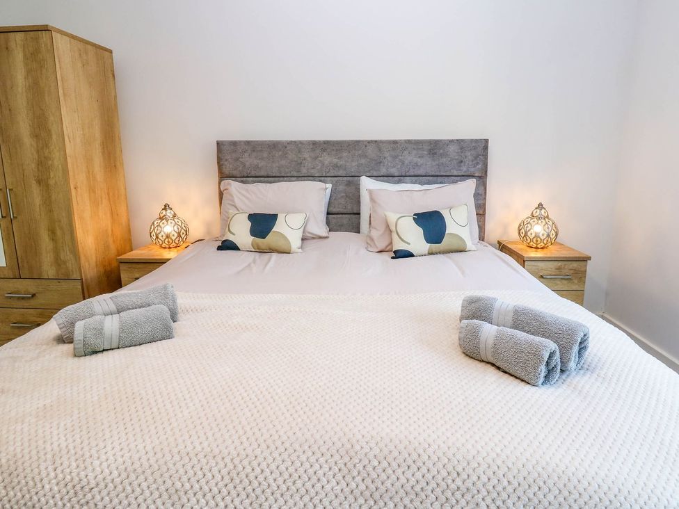 A bedroom with a bed and lamps at Sycamore Cottage in Frizington