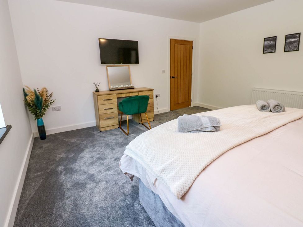 A bedroom with a bed and dresser at Sycamore Cottage in Frizington