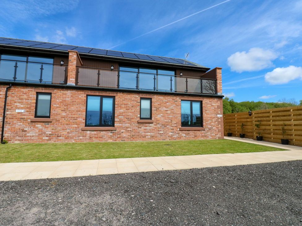 A house with a balcony and grass area at Silver Birch Cottage in Frizington