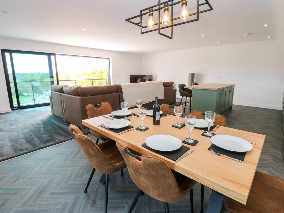 A dining area with a table set and a sofa visible at Silver Birch Cottage in Frizington