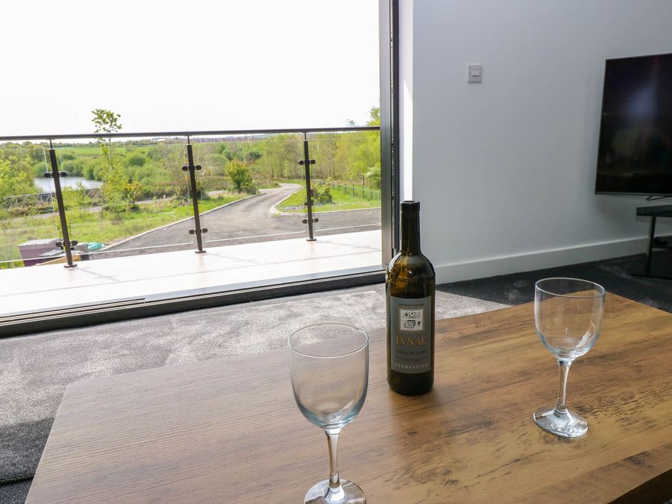 A living room with a wine bottle and glasses at Silver Birch Cottage in Frizington