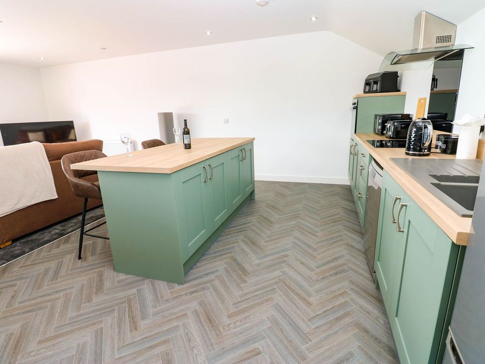 A kitchen with a green island and appliances at Silver Birch Cottage in Frizington