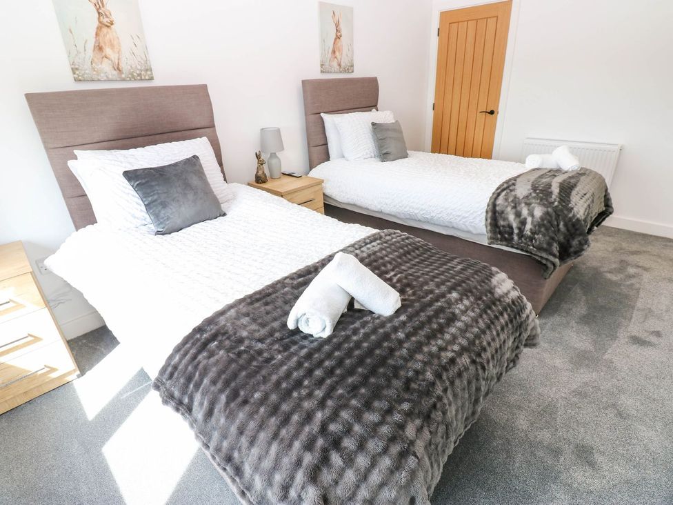 A bedroom with two single beds and a nightstand at Silver Birch Cottage in Frizington