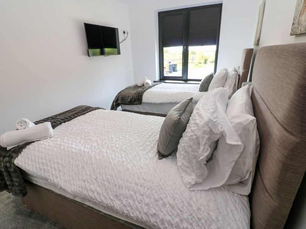 A bedroom with two beds and a television at Silver Birch Cottage in Frizington