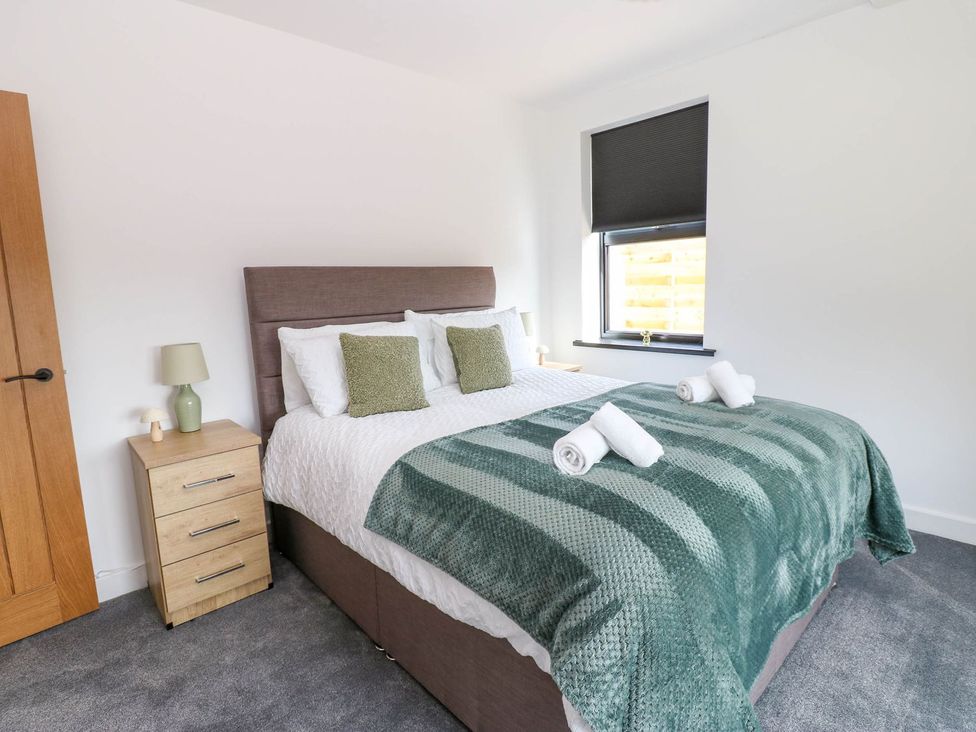 A bedroom with a bed and bedside table at Silver Birch Cottage in Frizington