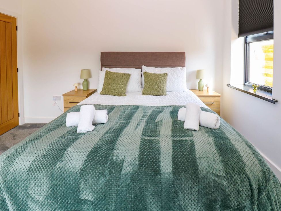 A bedroom with a bed and nightstand at Silver Birch Cottage in Frizington
