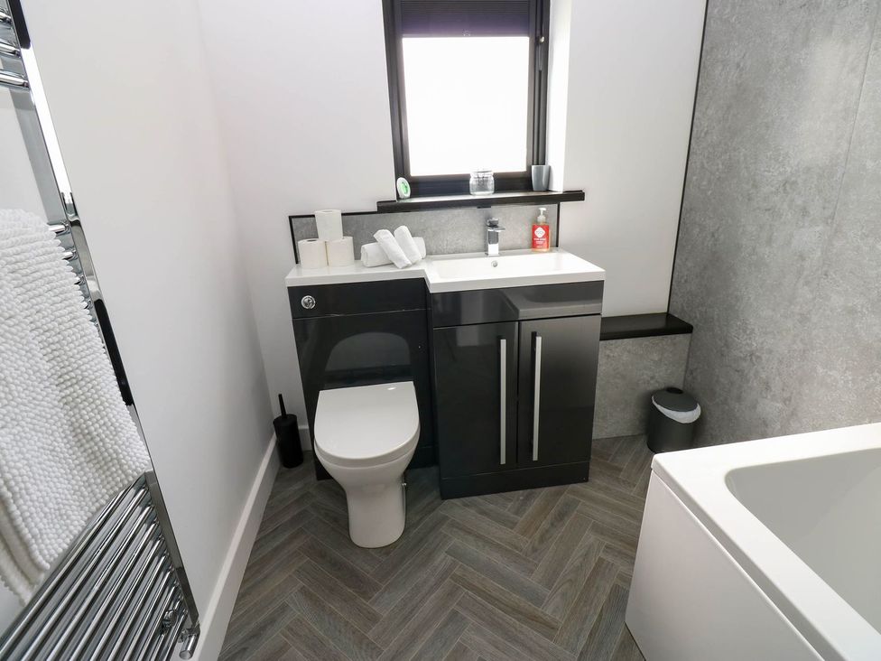 A bathroom featuring a toilet, sink, and bath at Silver Birch Cottage in Frizington