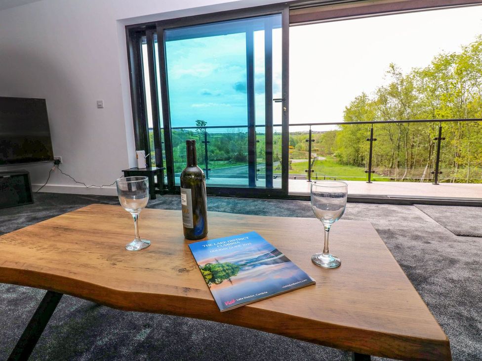 A living room with a table, wine and water glasses at Oak Tree Cottage in Frizington