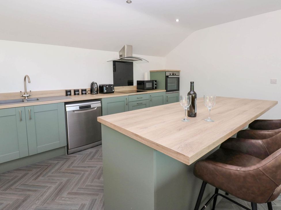 A kitchen with modern appliances and a breakfast bar at Oak Tree Cottage in Frizington