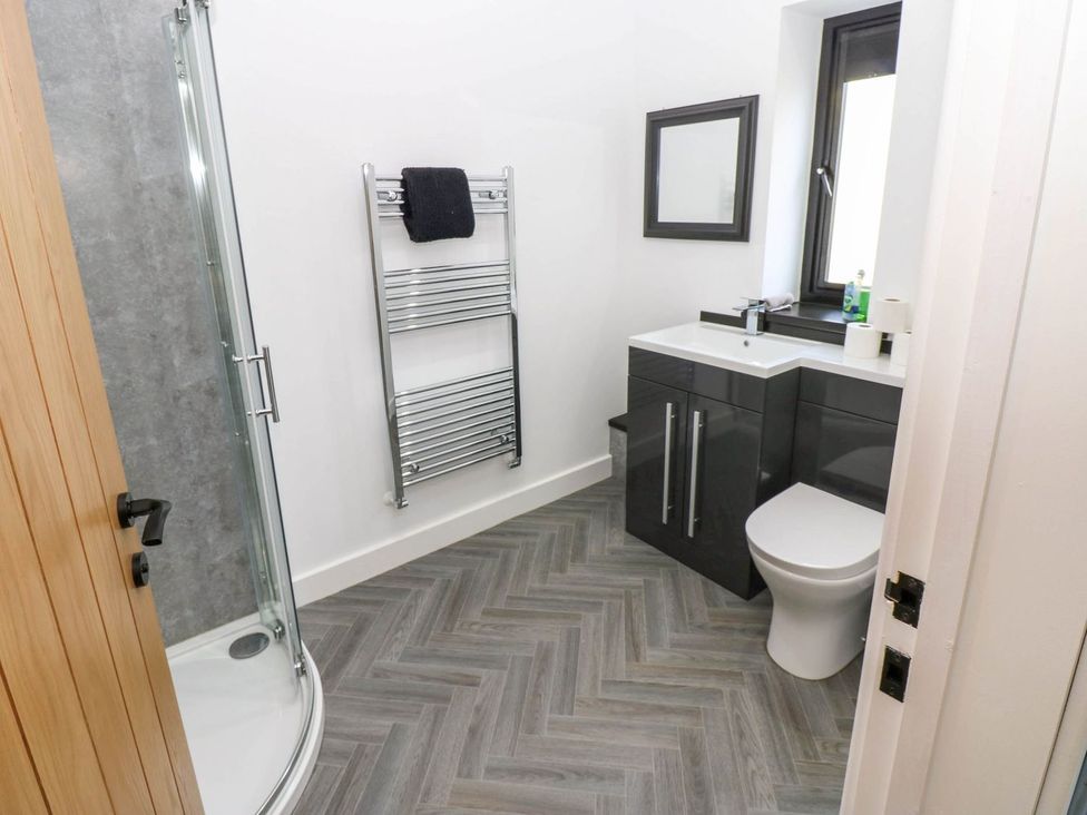 A bathroom with shower, sink, toilet and towel rail at Oak Tree Cottage in Frizington