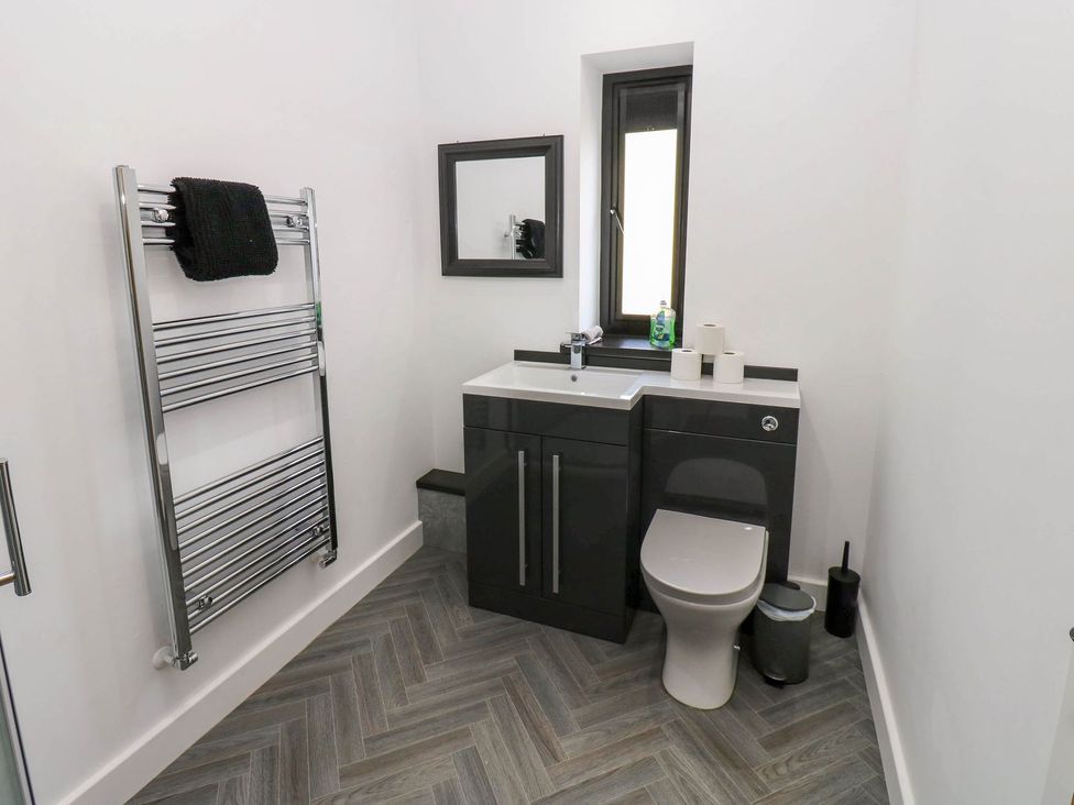 A bathroom with a sink, toilet, and towel rail at Oak Tree Cottage in Frizington