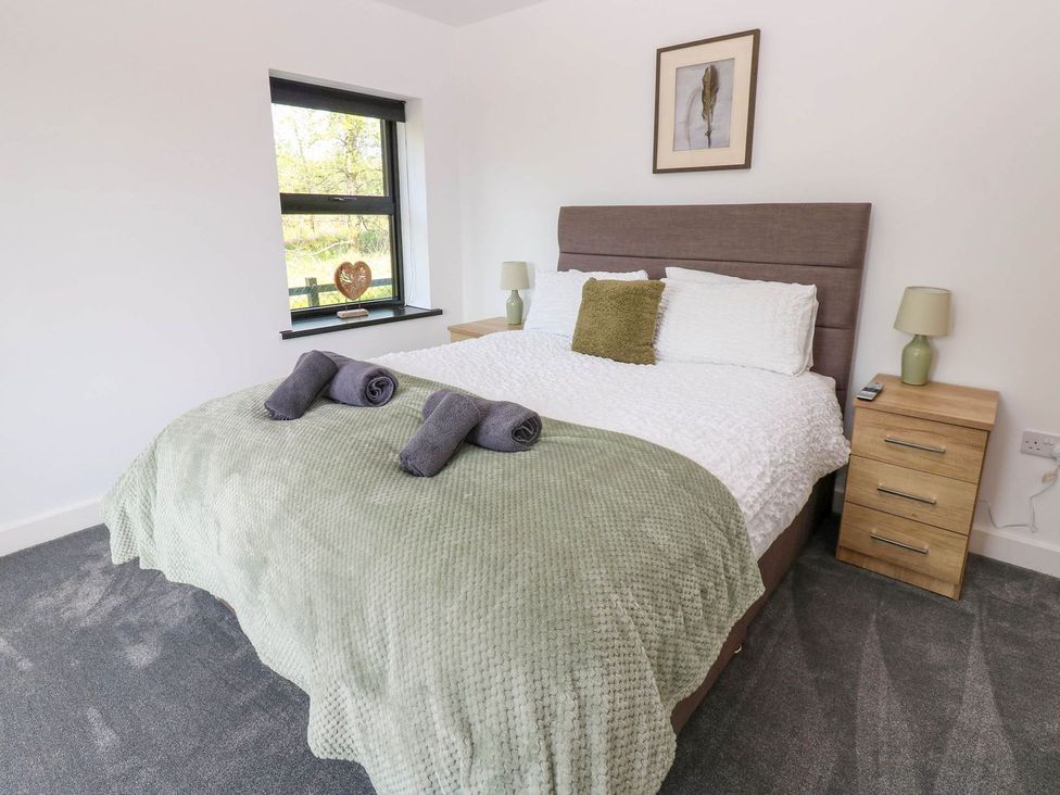 A bedroom with a double bed and bedside table at Oak Tree Cottage in Frizington