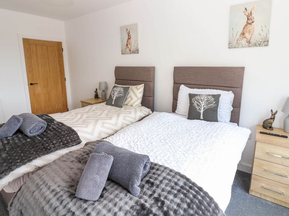 A bedroom with two beds and a bedside table at Oak Tree Cottage Frizington