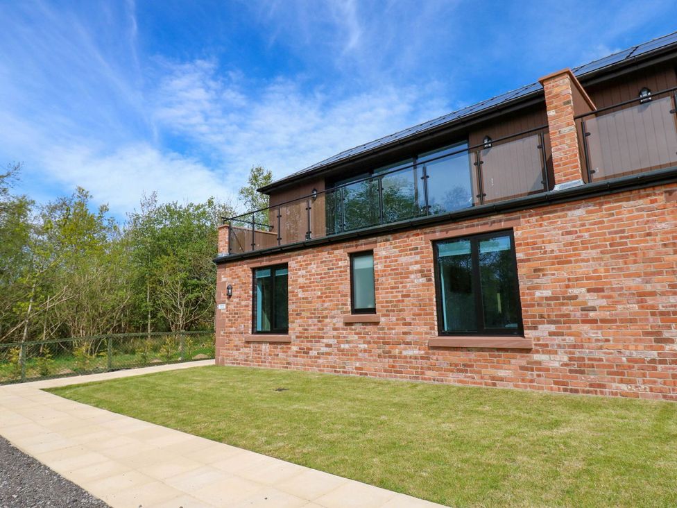 An outdoor area with a brick wall and windows at Oak Tree Cottage in Frizington