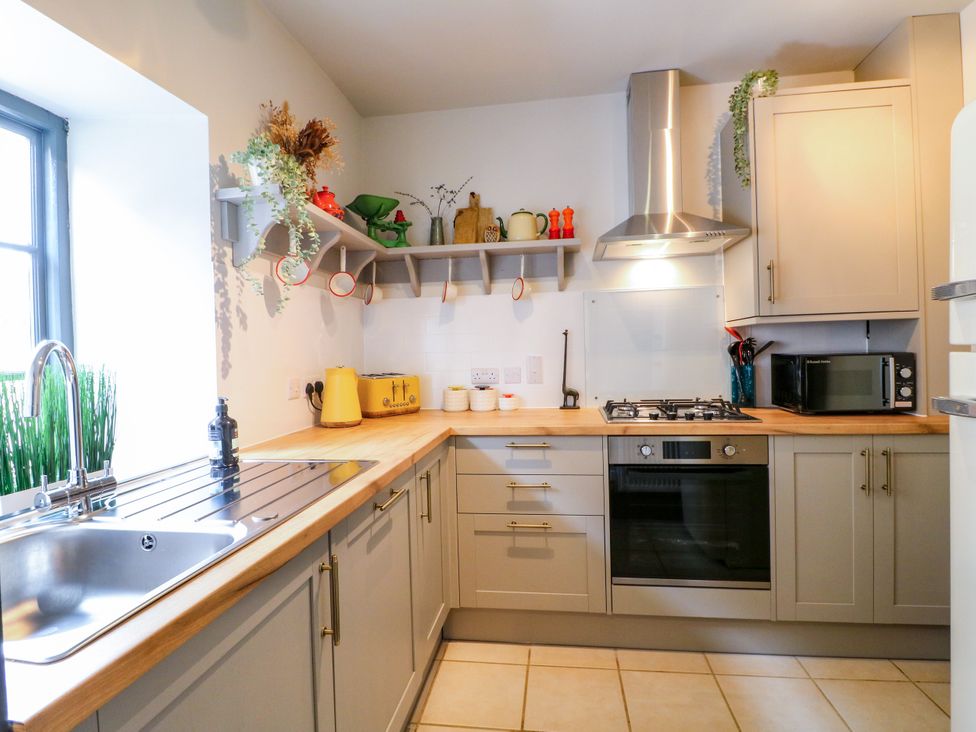 A kitchen with a sink, cooking stove, and microwave at Haarlem House in Wirksworth