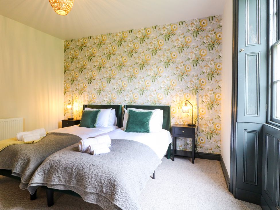 A bedroom with two beds and bedside tables at Haarlem House in Wirksworth