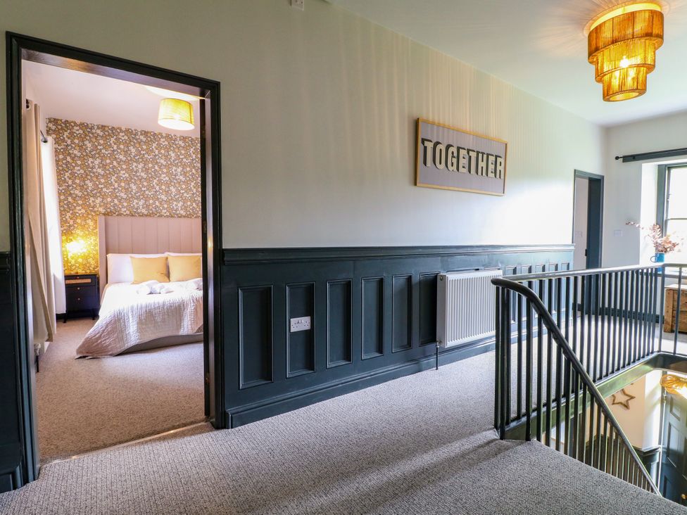 A hallway with a staircase and door leading to a bedroom at Haarlem House in Wirksworth