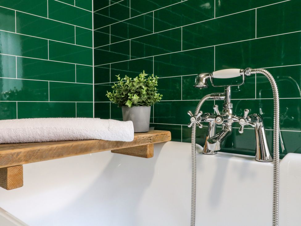 A bathtub with a wooden shelf and faucet at Haarlem House Wirksworth