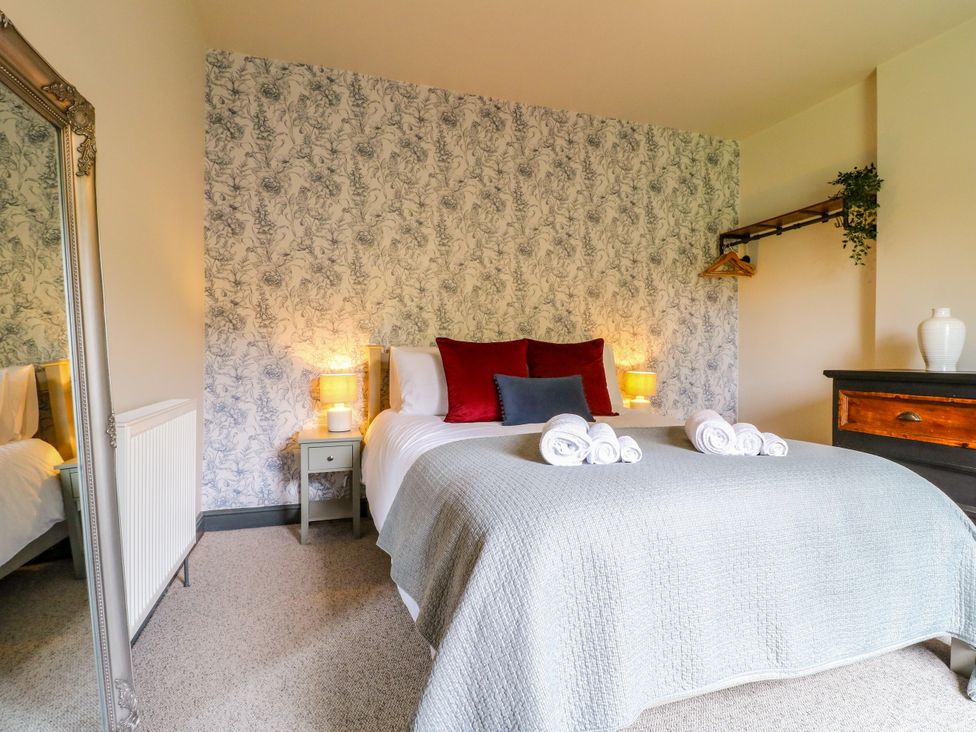 A bedroom featuring a bed, nightstand, and mirror at Haarlem House in Wirksworth