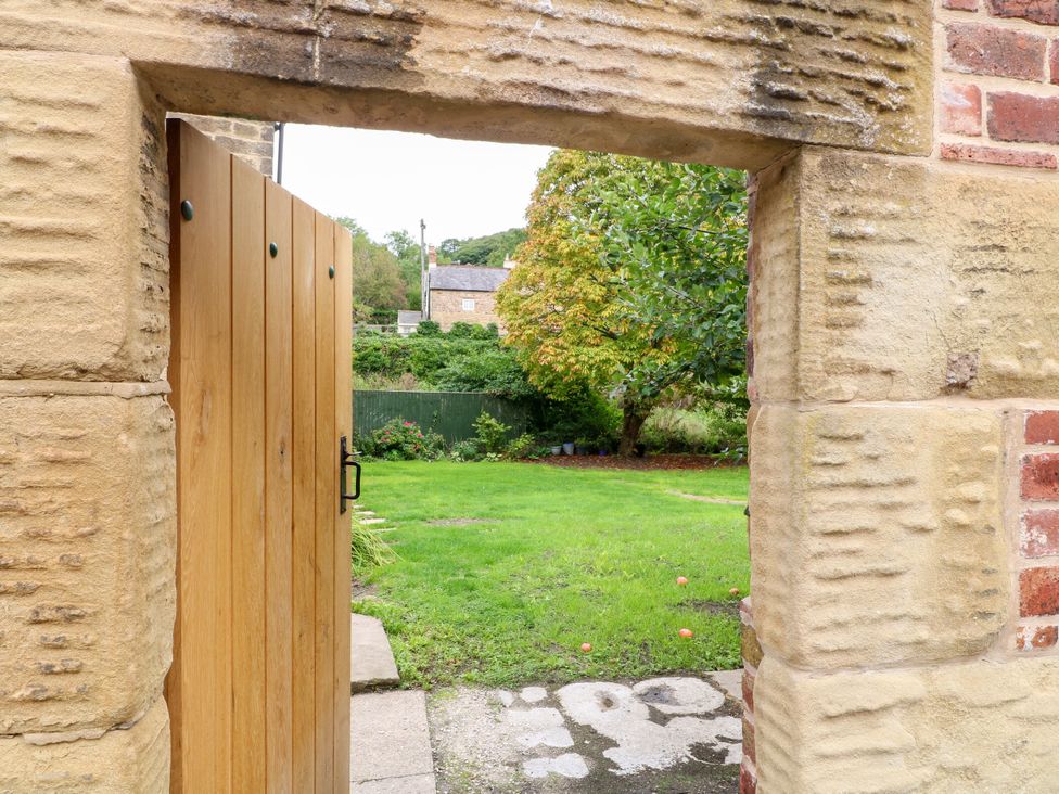 A garden viewed through a wooden gate at Haarlem House in Wirksworth