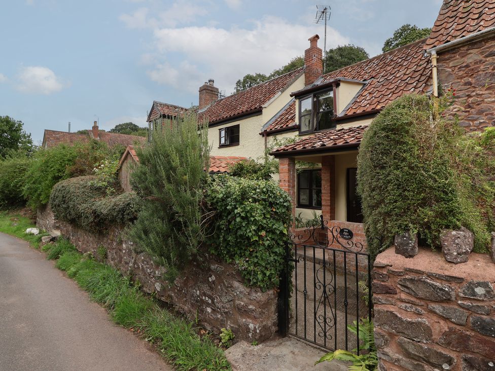 A cottage with a gated entrance and stone wall at The Cottage in Bridgwater