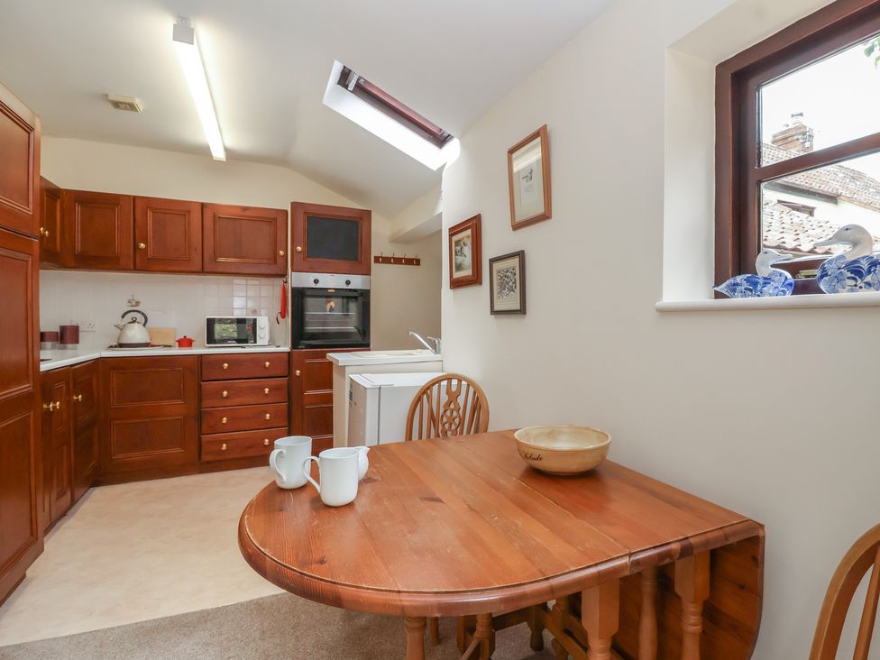 A kitchen with wooden cabinets and a table at The Cottage in Bridgwater